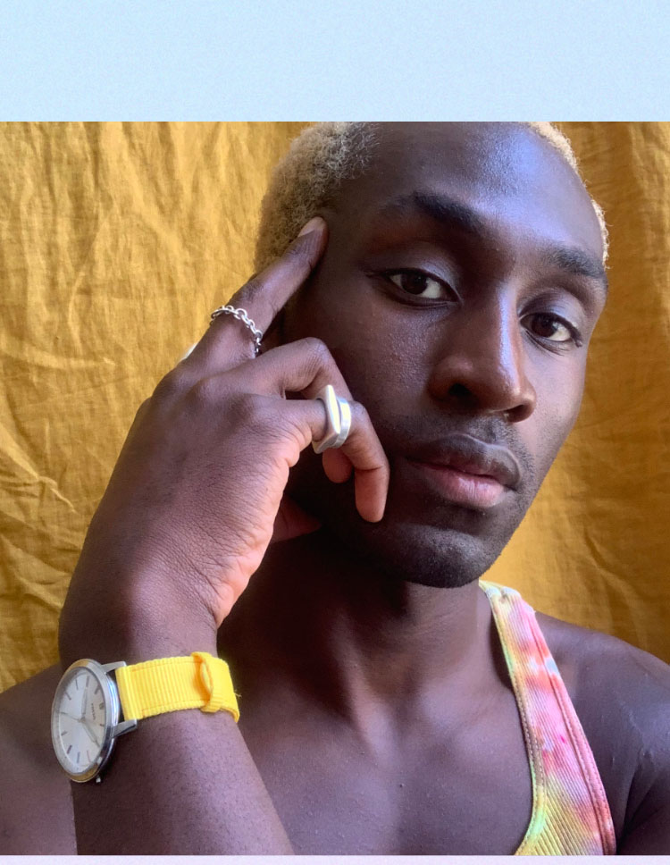 DeVonn Francis in front of a yellow background with yellow Pride watch