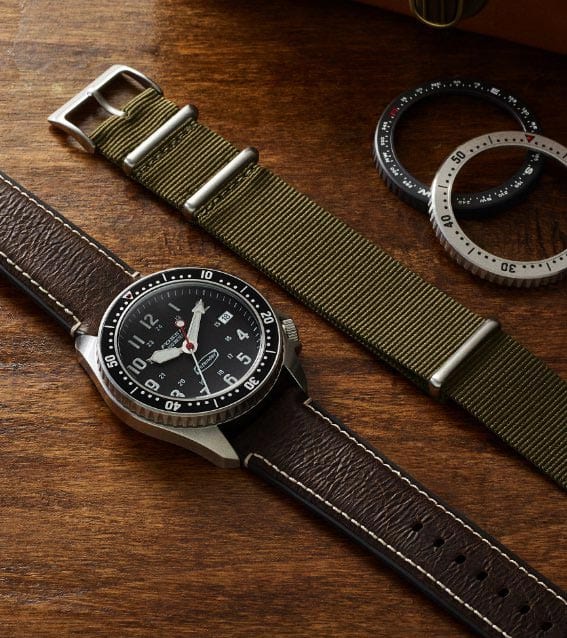 Defender watch beside extra strap and bezels.