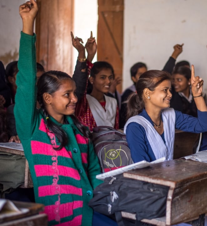 Un groupe de jeunes filles levant la main dans une salle de classe.