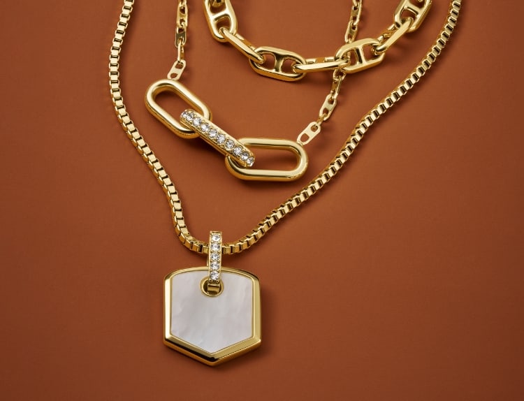 Tres collares de la colección de joyas Heritage de Fossil en tono dorado con nácar y detalles de cristal.